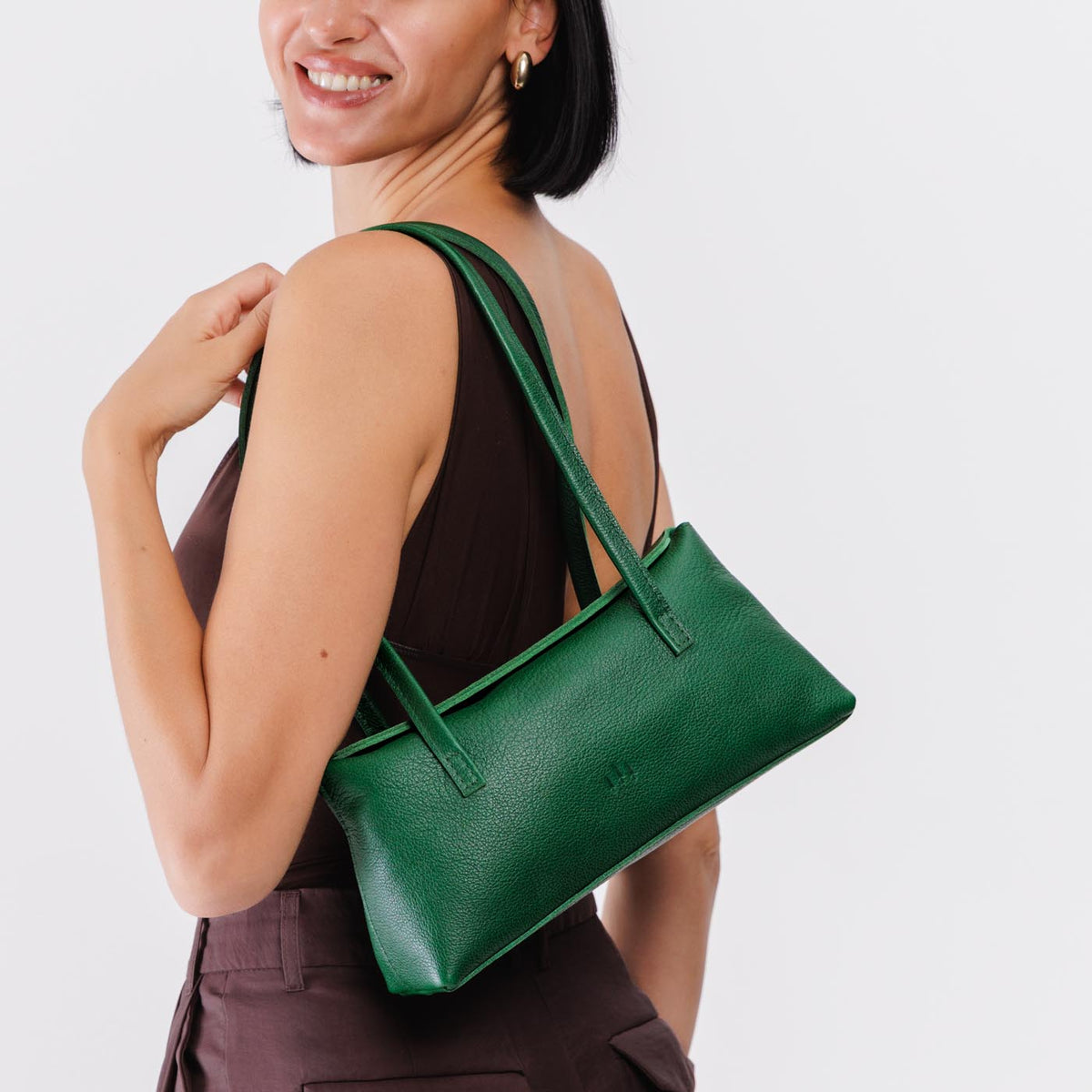 Bacalar | Woman wearing a dark green leather bowler bag against a white background