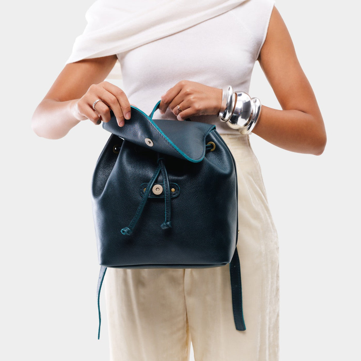 Boreal | Dark blue leather drawstring backpack being held by a person wearing a white shirt.