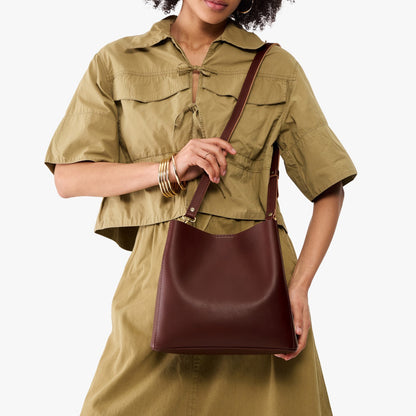 Cognac | Model wearing symmetrical bucket bag with latch closure and removable crossbody strap