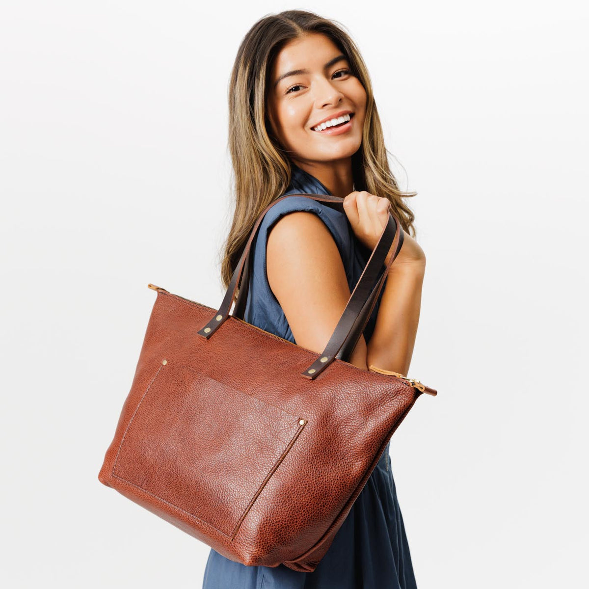 Nutmeg*Zipper | Model holding large zipper leather tote bag with sturdy bridle handles and front pocket