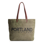 Green canvas tote bag with 'Portland Leather Goods' text and leather handles