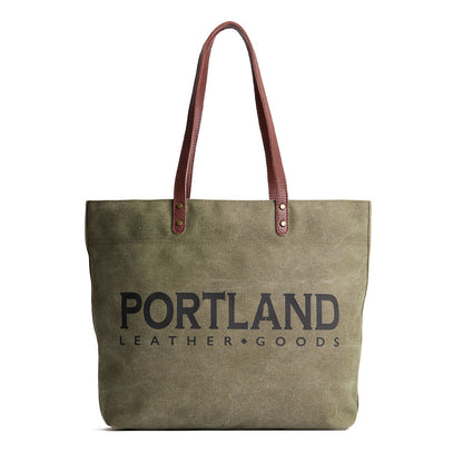 Green canvas tote bag with 'Portland Leather Goods' text and leather handles