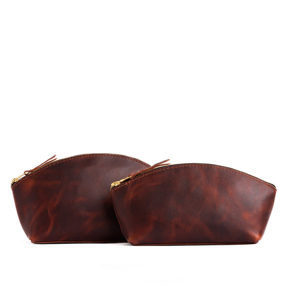 Lava | Size comparison shot of two spacious leather makeup bags with curved seams and top zipper