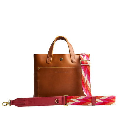 Tropical Punch | Patterned fabric and leather strap attached to leather purse on a white background