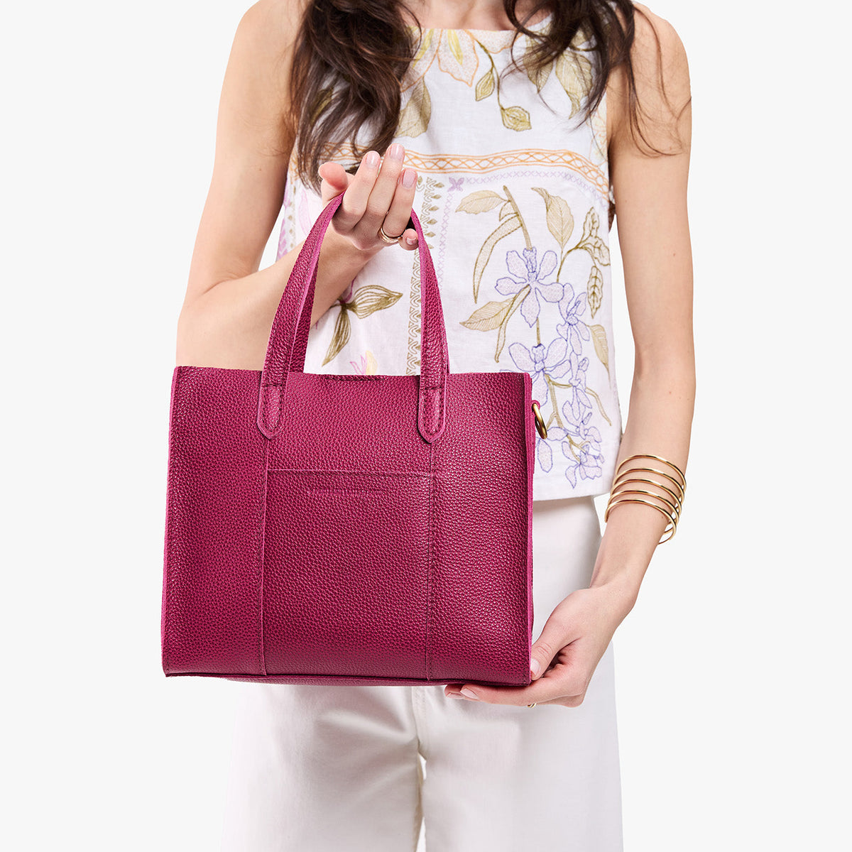 Cosmo | Model holding structured mid-size tote bag with overlapping panels and crossbody strap