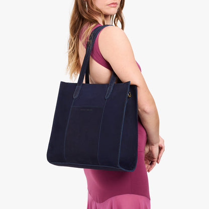 Velvet Blue*North/South | Model holding structured large tote bag with overlapping panels and crossbody strap