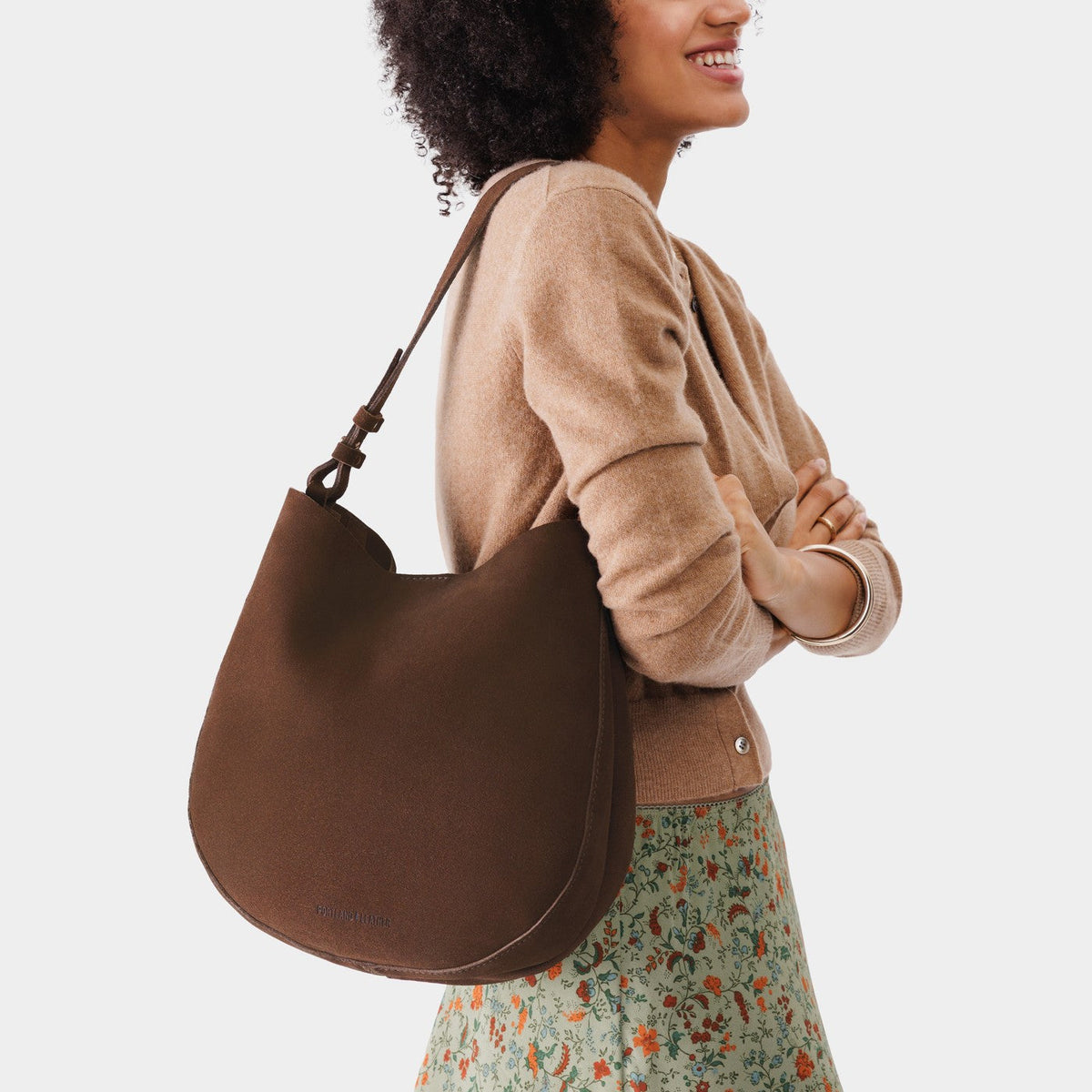 Stagecoach*Large | Woman wearing rounded shoulder bag with adjustable strap on a white background