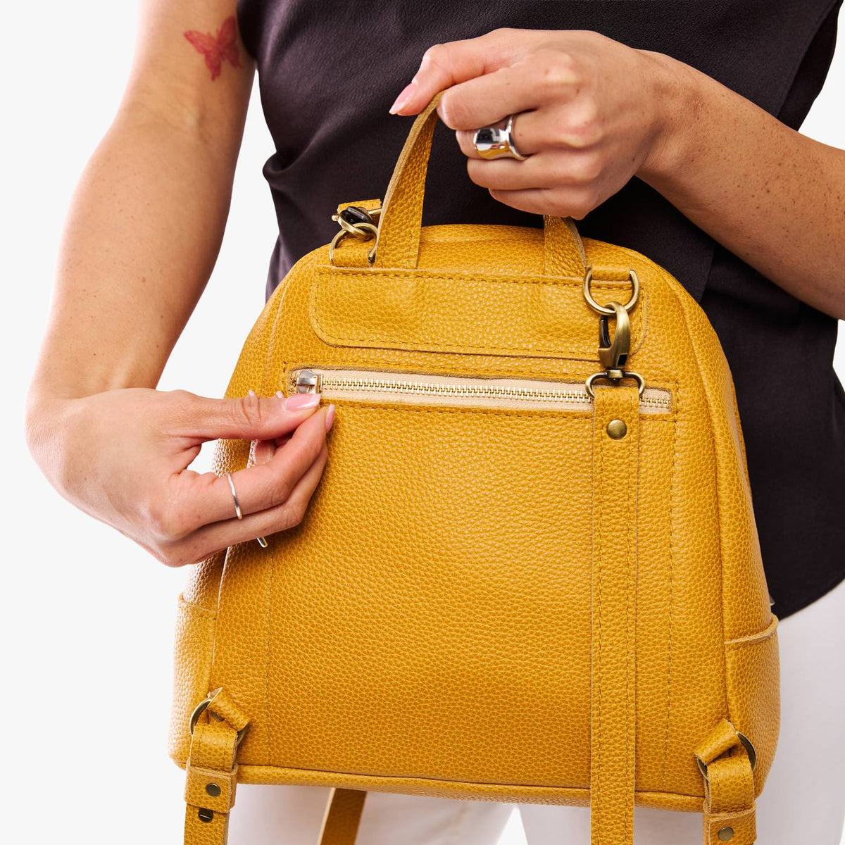 Sunshine | Model holding leather backpack with back zipper pocket