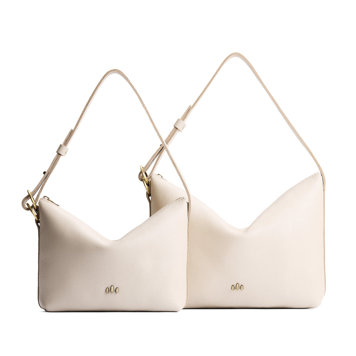 Pebbled Bone | Size comparison shot of small and large slouchy leather shoulder bags with zipper opening and three metal tree emblems