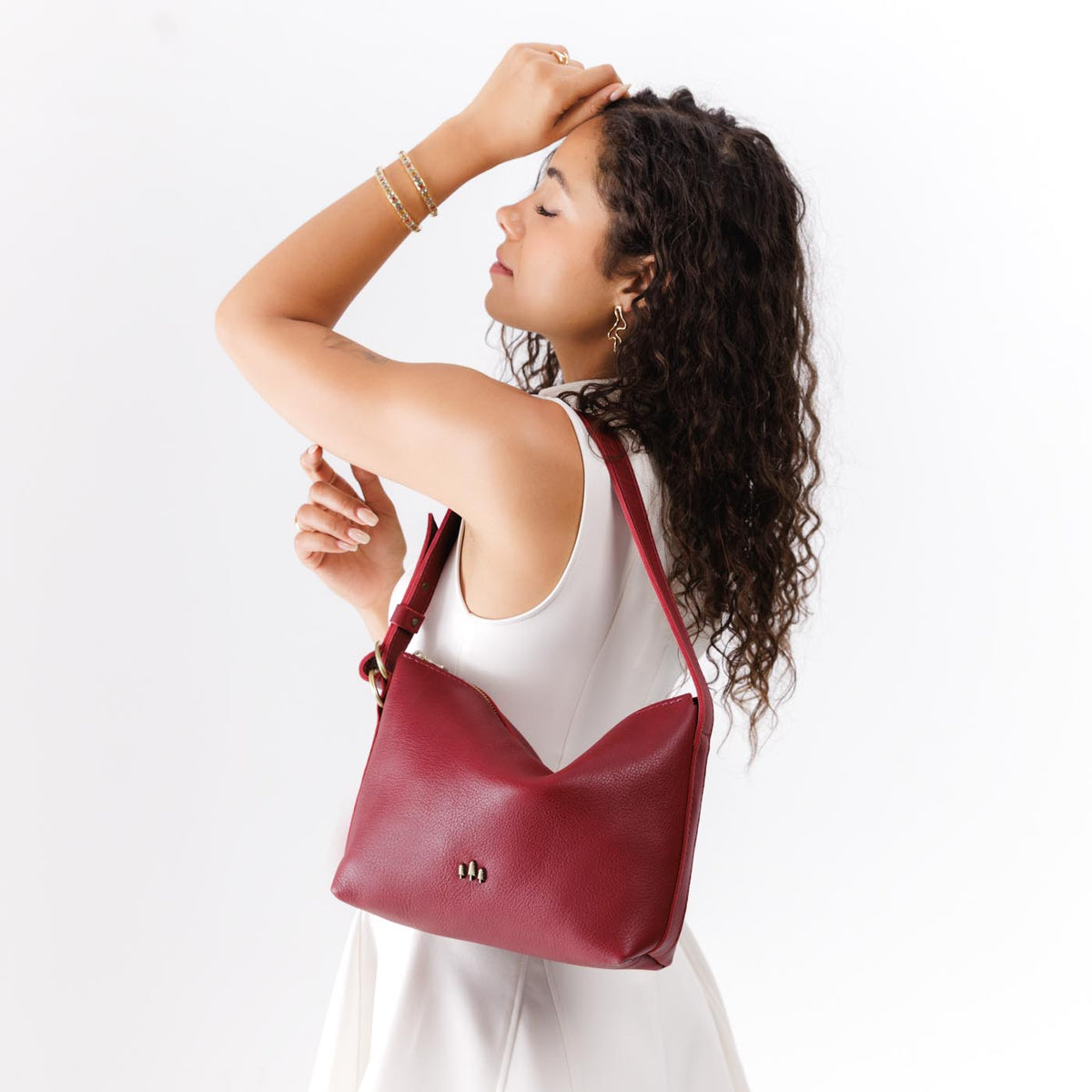 Flamenco*Small | Model wearing petite slouchy leather shoulder bag with zipper opening and three metal tree emblems
