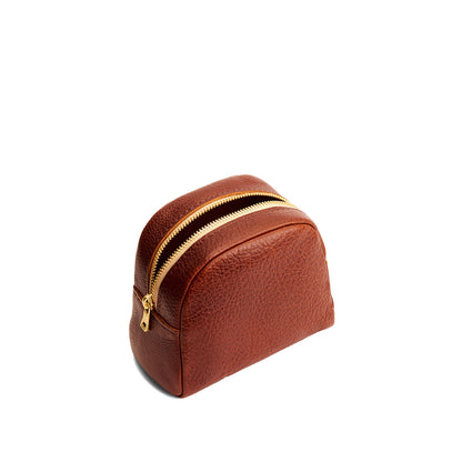 Nutmeg | Curved top leather pouch with zipper opening, flat base, and three metal tree emblems in front